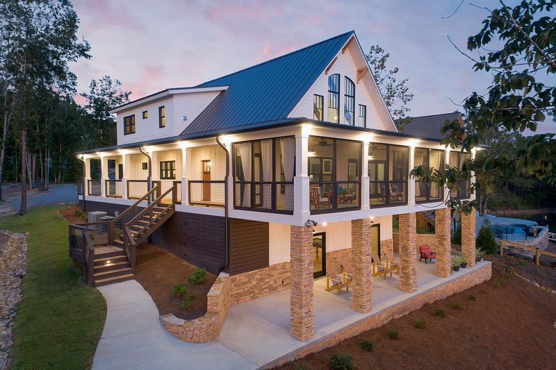 Lakefront farmhouse at twilight, Central Alabama. Home designed by Brian Eicholtz.